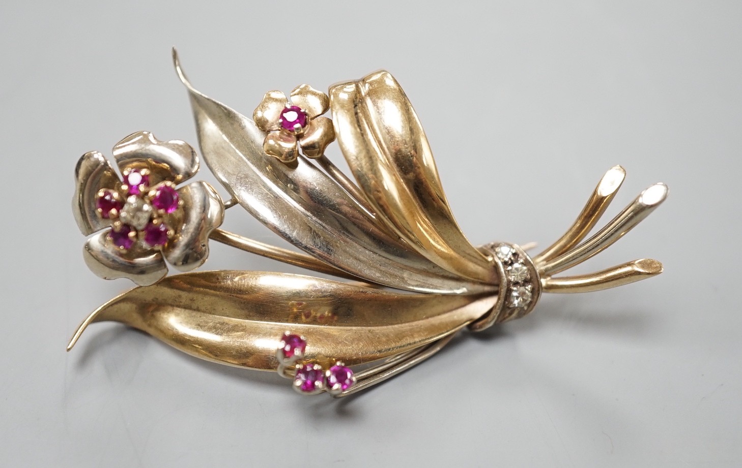 A two colour yellow metal, ruby and diamond cluster set floral spray brooch, 51mm, gross weight 8.2 grams.